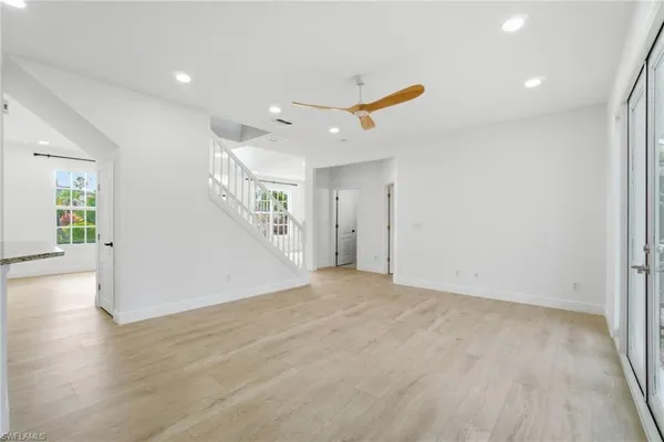 a view of an empty room with wooden floor and a ceiling fan