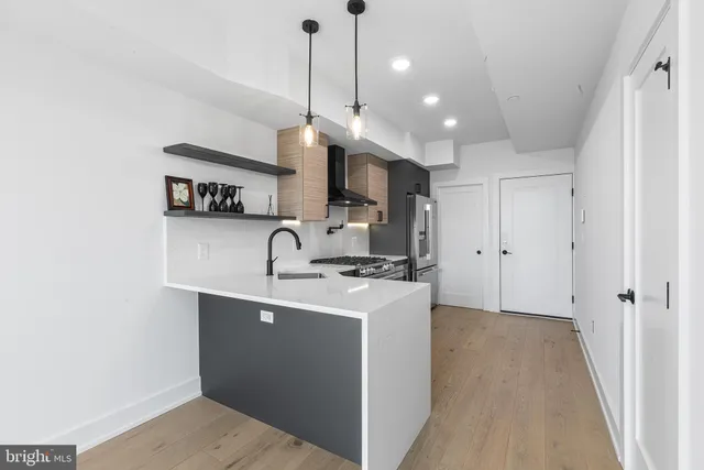 a view of a kitchen with kitchen island a sink stainless steel appliances and cabinets