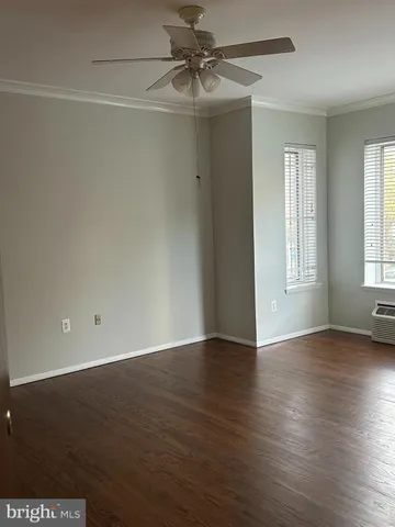 an empty room with wooden floor chandelier fan and windows