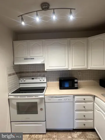 a kitchen with granite countertop white cabinets and white appliances
