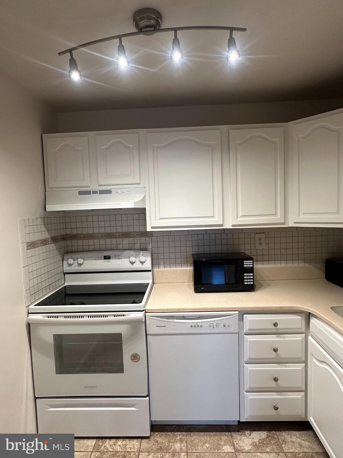 2120 N Street Northwest, Unit 101 Washington, DC 20037 - Photo 18 of 21 a kitchen with granite countertop white cabinets and white appliances