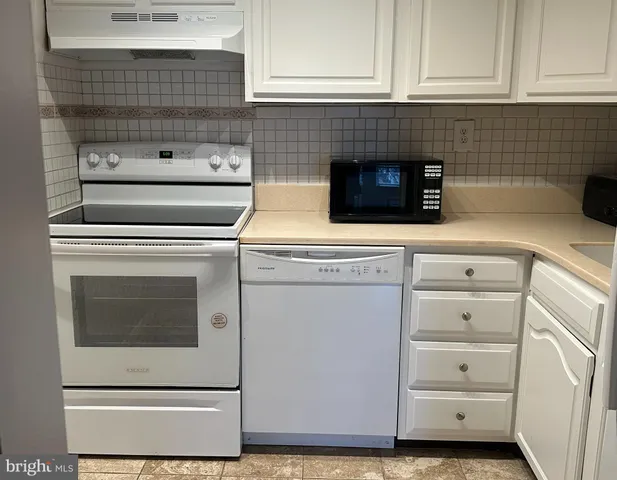 a kitchen with granite countertop white cabinets and white appliances