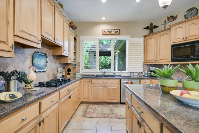 a kitchen with stainless steel appliances granite countertop a sink a stove and a wooden floors