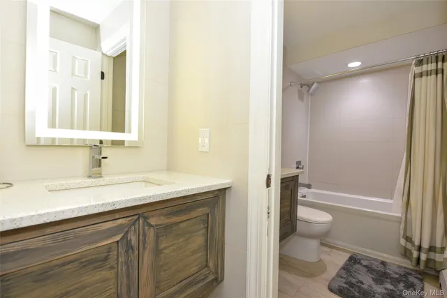 a bathroom with a shower sink vanity mirror and toilet