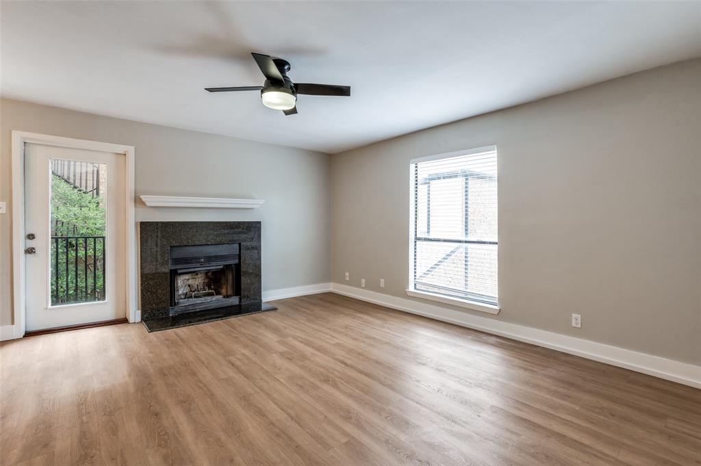 an empty room with windows fireplace and wooden floor