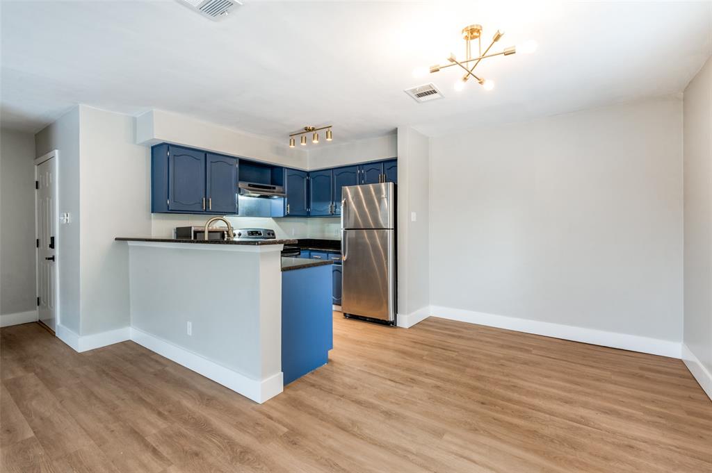 3022 Forest Lane, Unit 315 Dallas, TX 75234 - Photo 4 of 12 a kitchen with stainless steel appliances granite countertop a refrigerator a stove top oven a sink and dishwasher with wooden floor