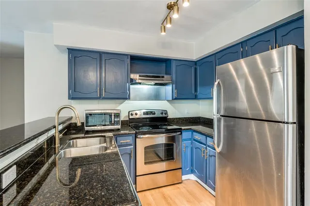 a kitchen with granite countertop a refrigerator stove and sink