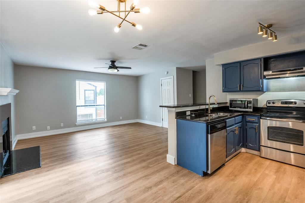 3022 Forest Lane, Unit 315 Dallas, TX 75234 - Photo 6 of 12 a kitchen with granite countertop a stove and a wooden floor