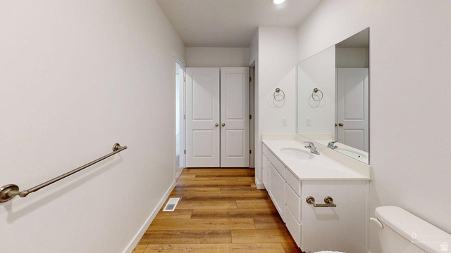 783 Pheasantbrook Drive, Unit 2A Centerville, UT 84014 - Photo 17 of 41 Contemporary bathroom featuring a long single vanity with an integrated sink, a large mirror, dual closet doors, wood-finish flooring, and recessed lighting