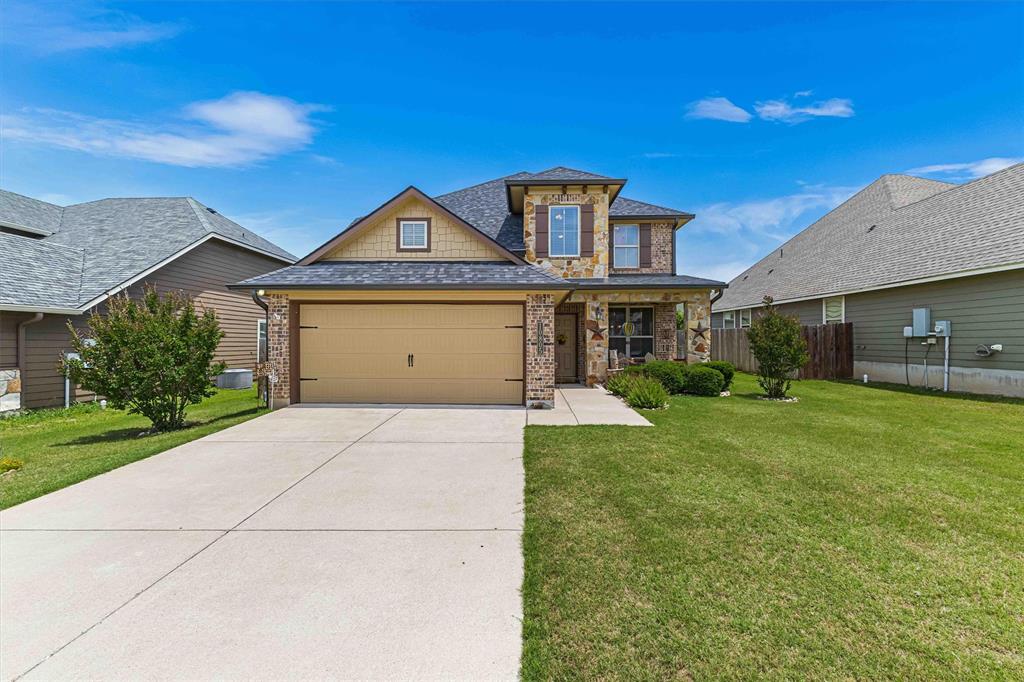View of front of home featuring driveway, an attached garage, brick siding, and roof with shingles