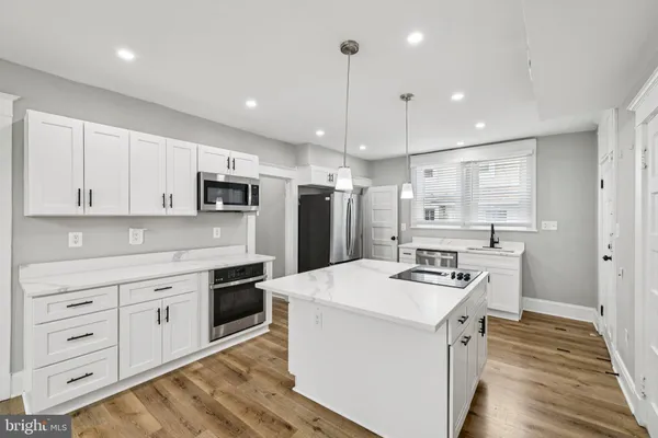 a kitchen that has a lot of white cabinets and stainless steel appliances