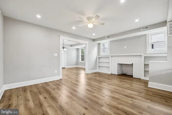a view of an empty room with wooden floor fireplace and a window