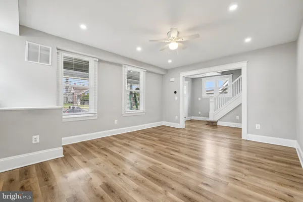 a view of an empty room with wooden floor and window