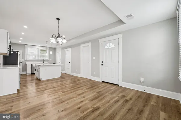 a view of a kitchen with kitchen island stainless steel appliances sink cabinets and wooden floor
