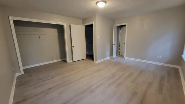 an empty room with wooden floor & closet area