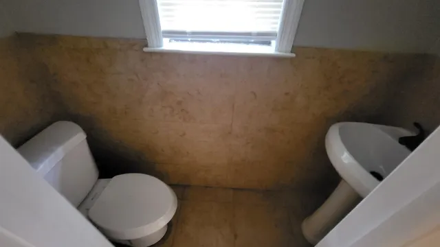 a bathroom with a toilet and a chair