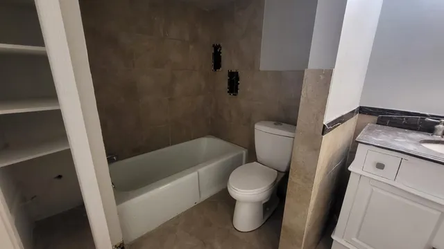 a white toilet sitting next to a bath tub