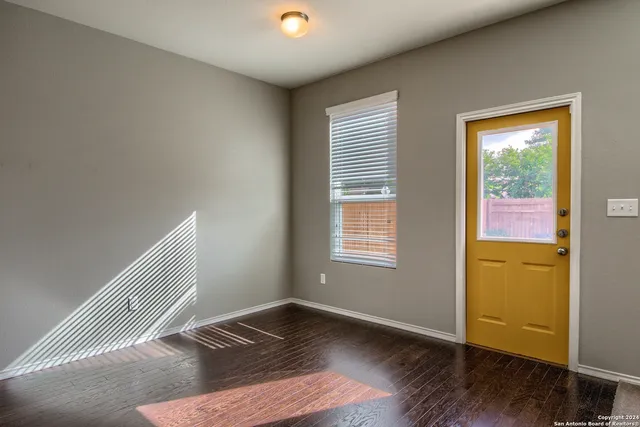 a view of an empty room with wooden floor and a window