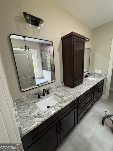 a bathroom with a granite countertop double vanity sink and mirror