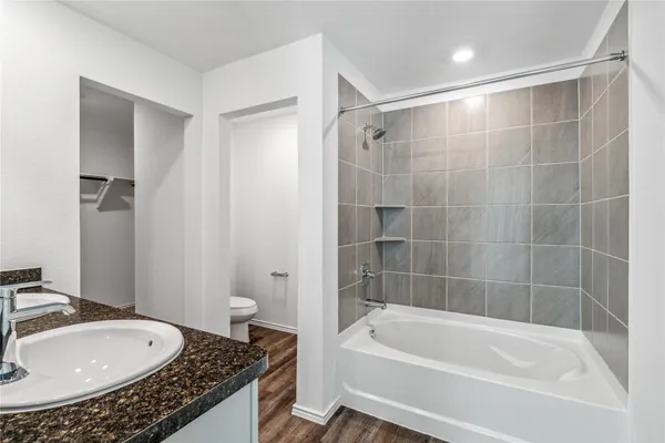 a bathroom with a granite countertop sink a toilet and bathtub