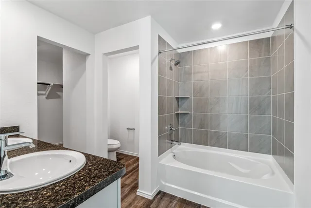 a bathroom with a granite countertop sink a toilet and bathtub