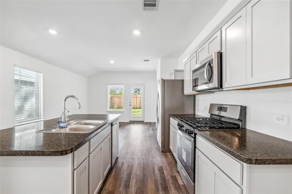 a kitchen with granite countertop a sink a stove and cabinets