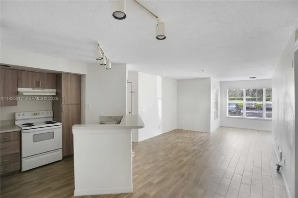 a kitchen that has a sink a stove and wooden floor