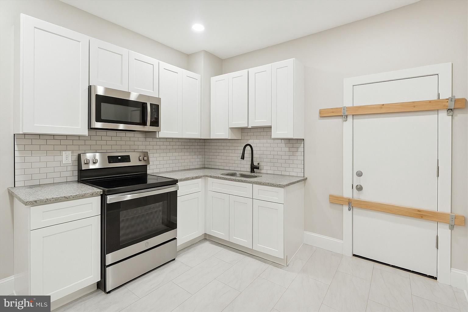 3047 Fontain Street Philadelphia, PA 19121 - Photo 3 of 15 a kitchen with granite countertop white cabinets sink and stainless steel appliances