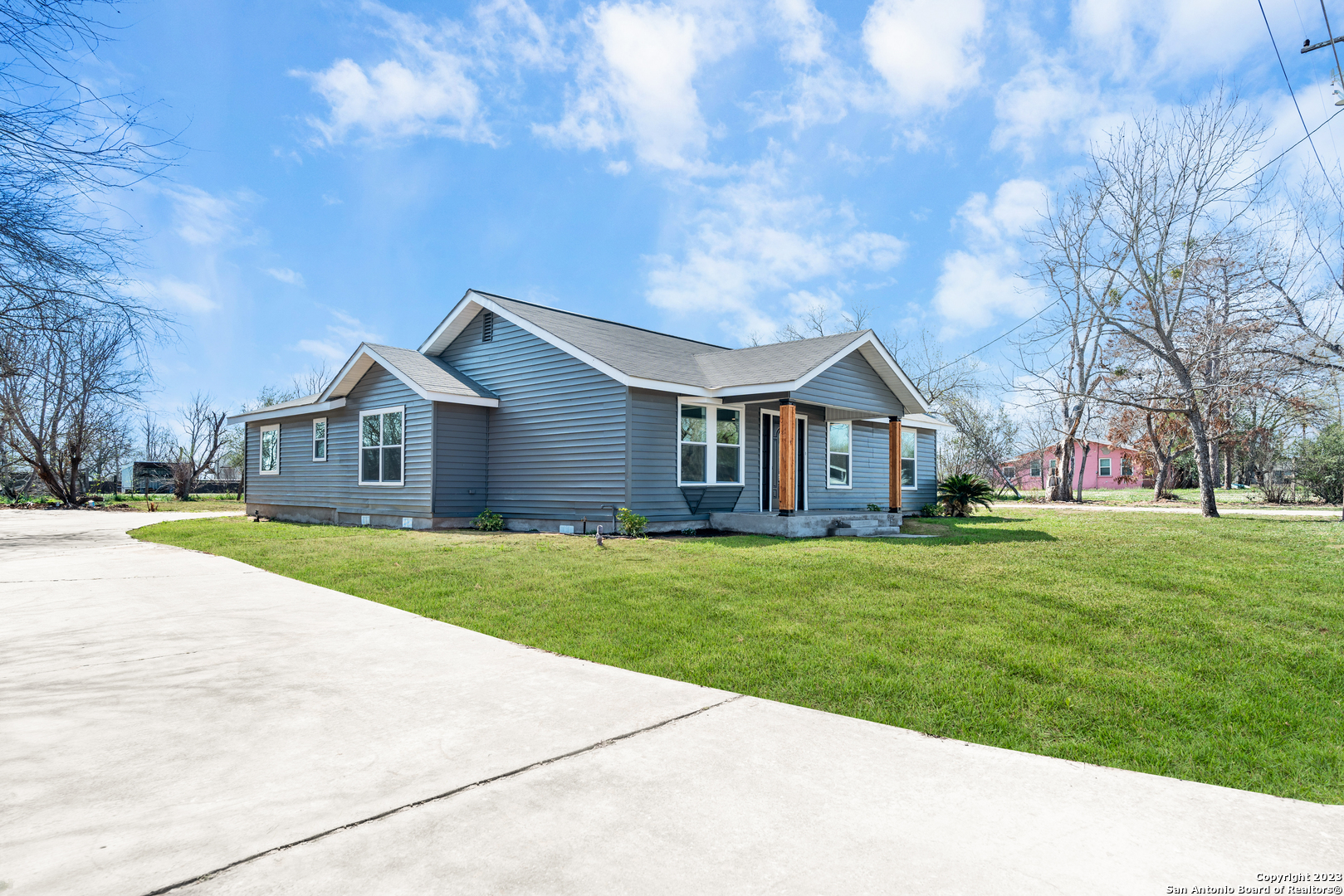 a view of a yard in front of a house with large trees