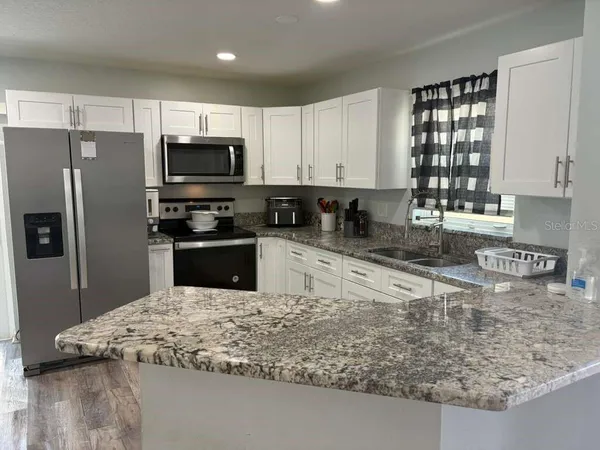 a kitchen with granite countertop a sink a counter top space appliances and cabinets
