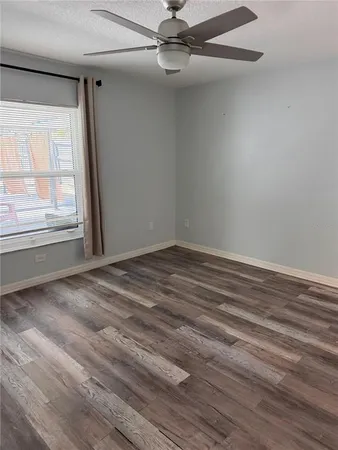 an empty room with wooden floor fan and windows