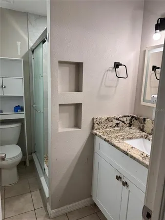 a bathroom with a granite countertop sink a toilet and a mirror