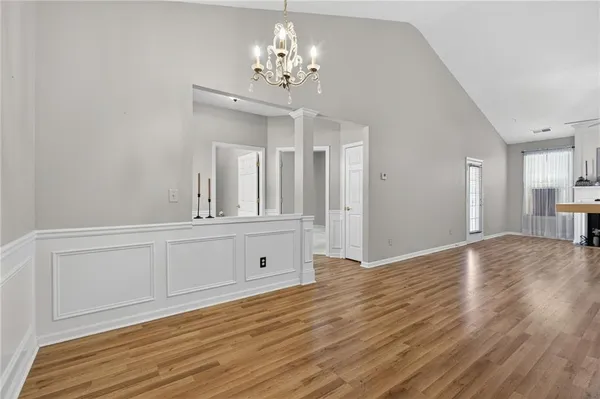 a view of a hallway with wooden floor and chandelier