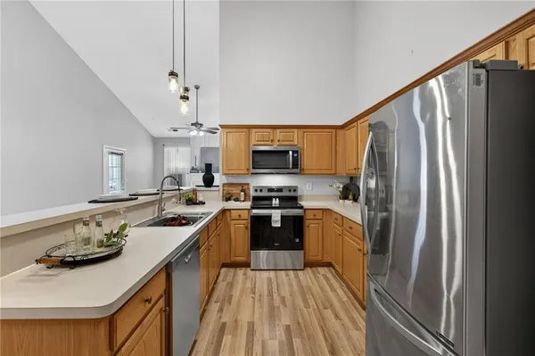 a kitchen with stainless steel appliances granite countertop a refrigerator a stove and a sink with wooden floor