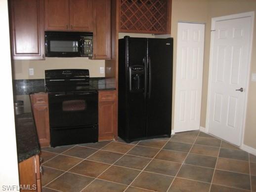 a view of a refrigerator in kitchen and an empty room with wooden floor