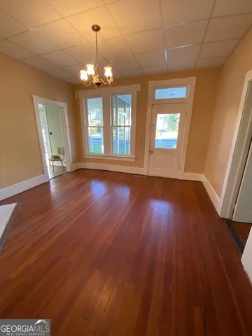a view of an empty room with wooden floor and a window