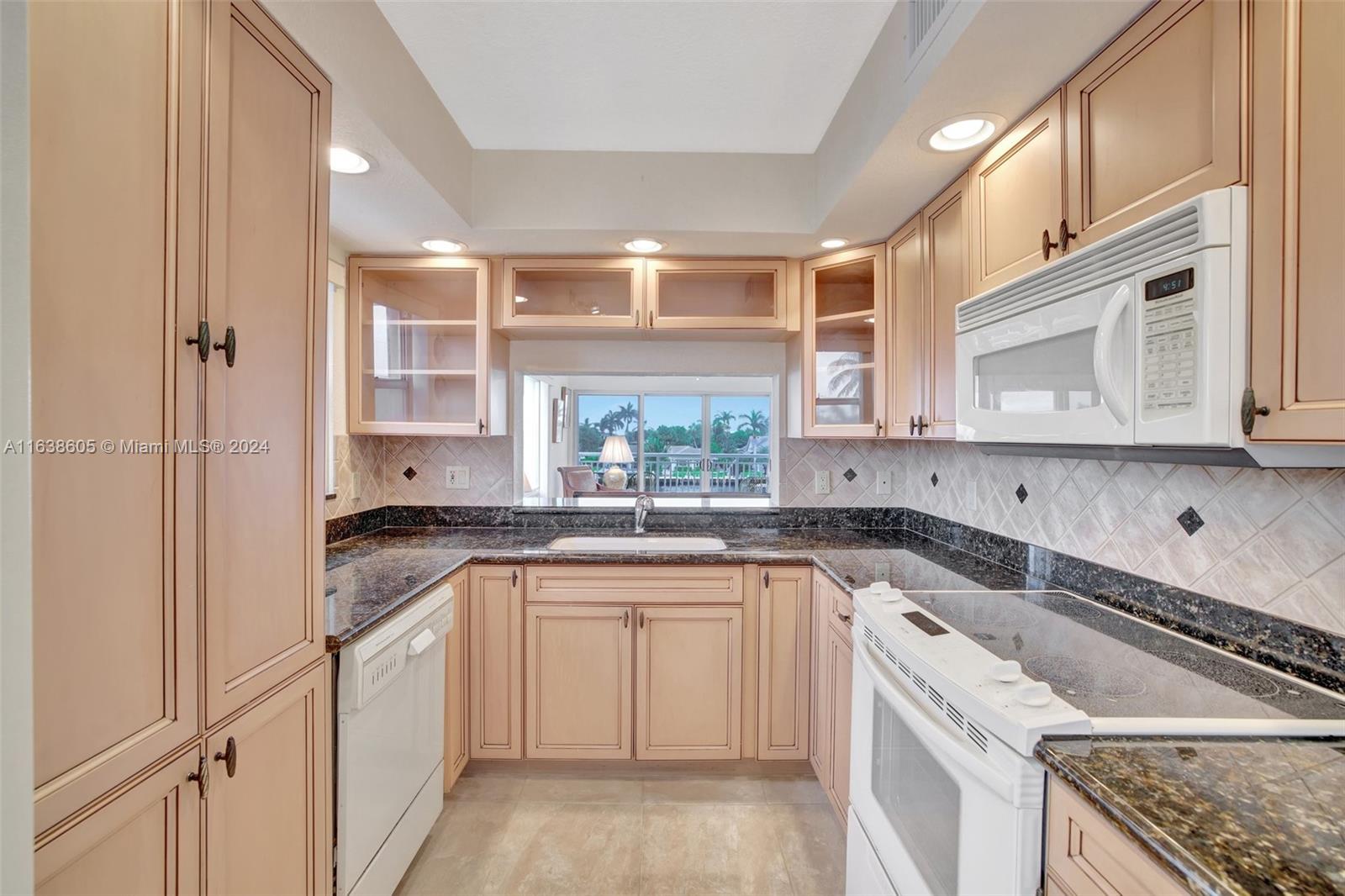 2611 North Riverside Drive, Unit 301 Pompano Beach, FL 33062 - Photo 4 of 31 a kitchen with granite countertop a sink stove and cabinets