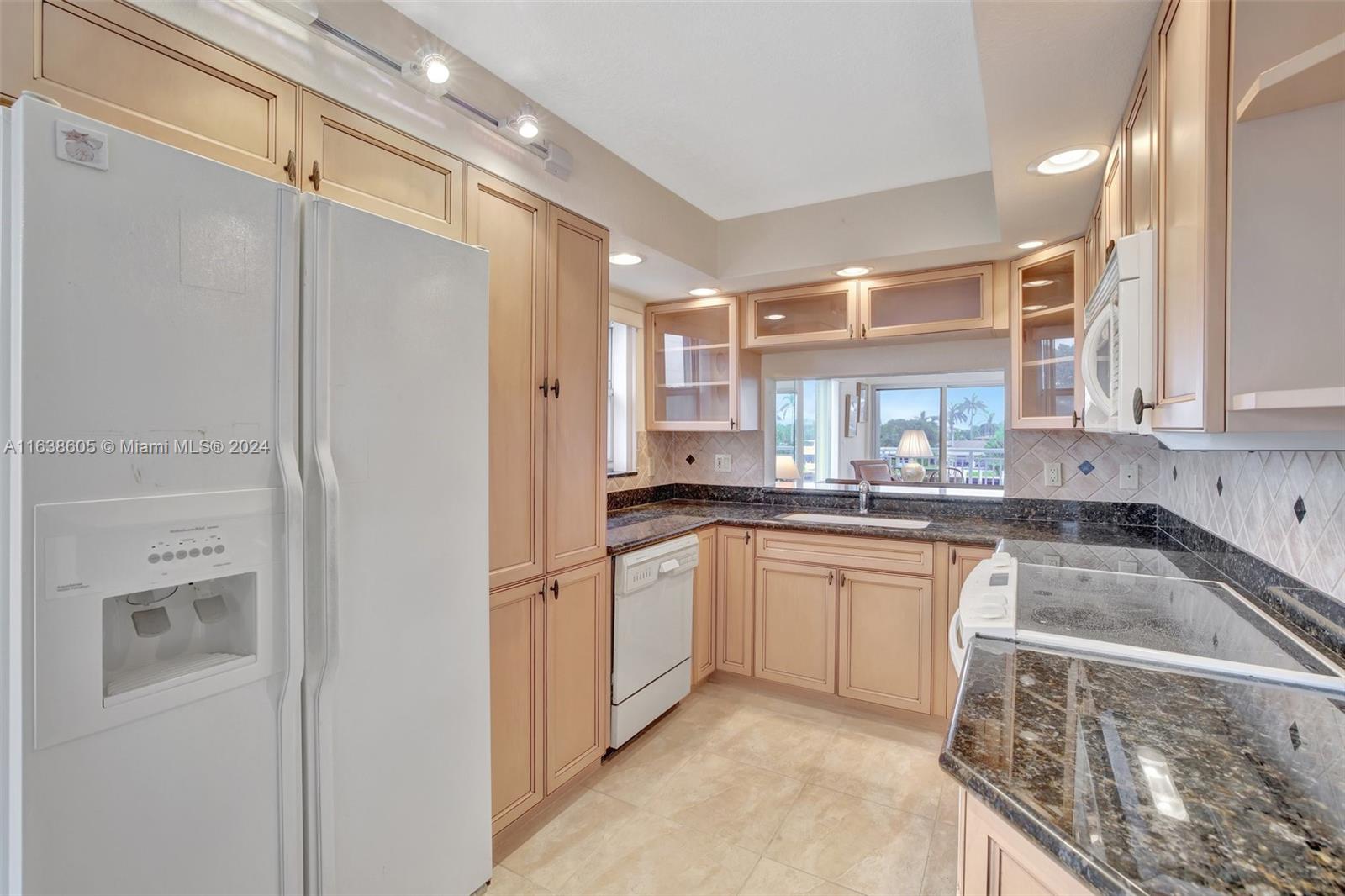 2611 North Riverside Drive, Unit 301 Pompano Beach, FL 33062 - Photo 5 of 31 a kitchen with a refrigerator a sink and cabinets