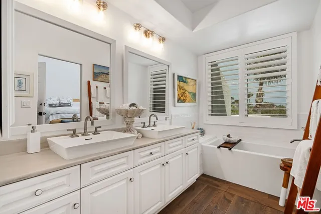 a bathroom with a sink double vanity mirror and a bathtub