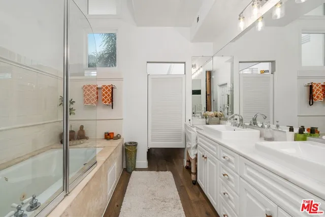 a bathroom with a double vanity sink a mirror and a bathtub