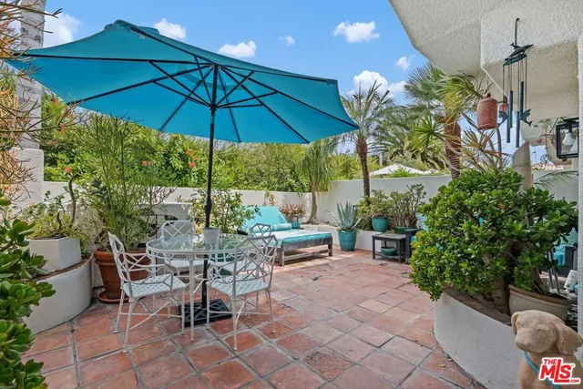 a view of a tables and chairs under an umbrella in backyard