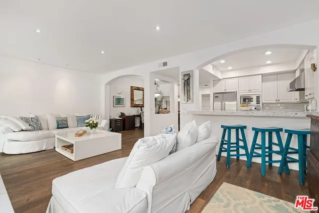 a living room with furniture wooden floor and kitchen view