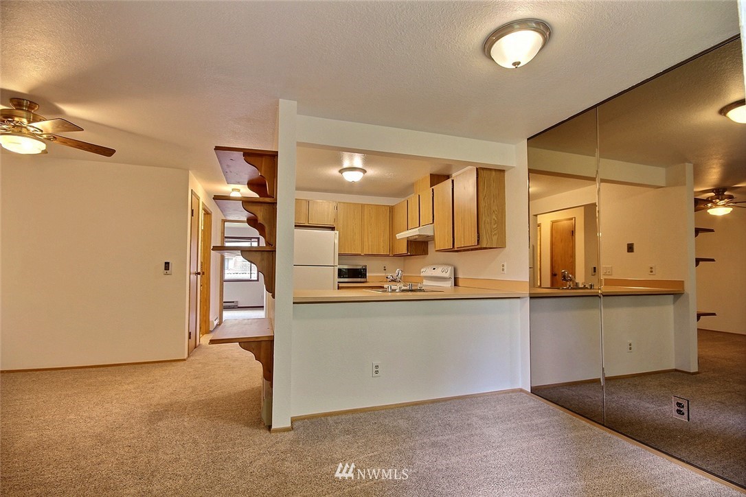 17419 119th Lane Southeast, Unit E31 Renton, WA 98058 - Photo 4 of 18 a kitchen with stainless steel appliances granite countertop a sink and dishwasher a refrigerator with wooden floor