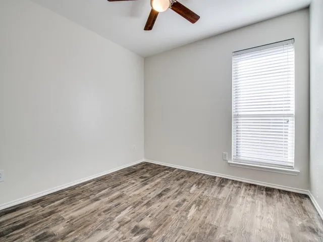 an empty room with a window and a ceiling fan
