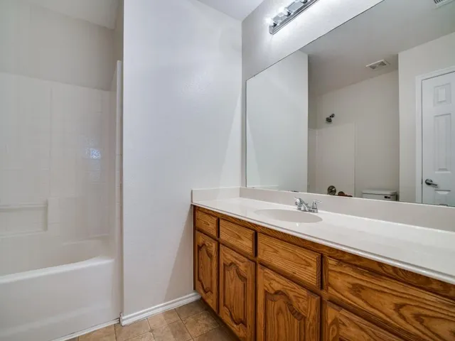 a bathroom with a granite countertop sink and a bathtub