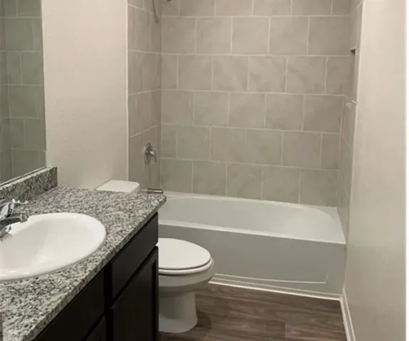 a bathroom with a granite countertop bathtub shower sink vanity and toilet
