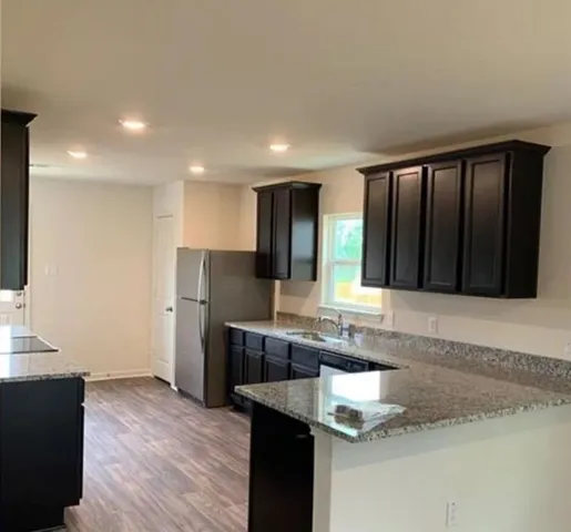 a kitchen with stainless steel appliances kitchen island granite countertop a refrigerator and a sink