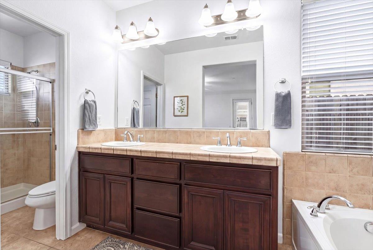2036 Vignolia Loop Roseville, CA 95747 - Photo 19 of 27 a bathroom with a granite countertop sink a toilet and a large mirror