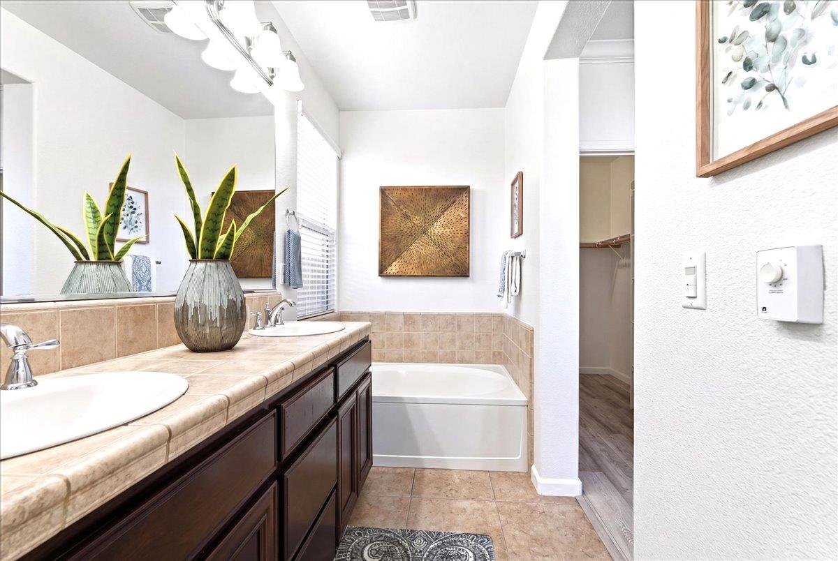 2036 Vignolia Loop Roseville, CA 95747 - Photo 20 of 27 a bathroom with a granite countertop sink a large mirror and a bathtub