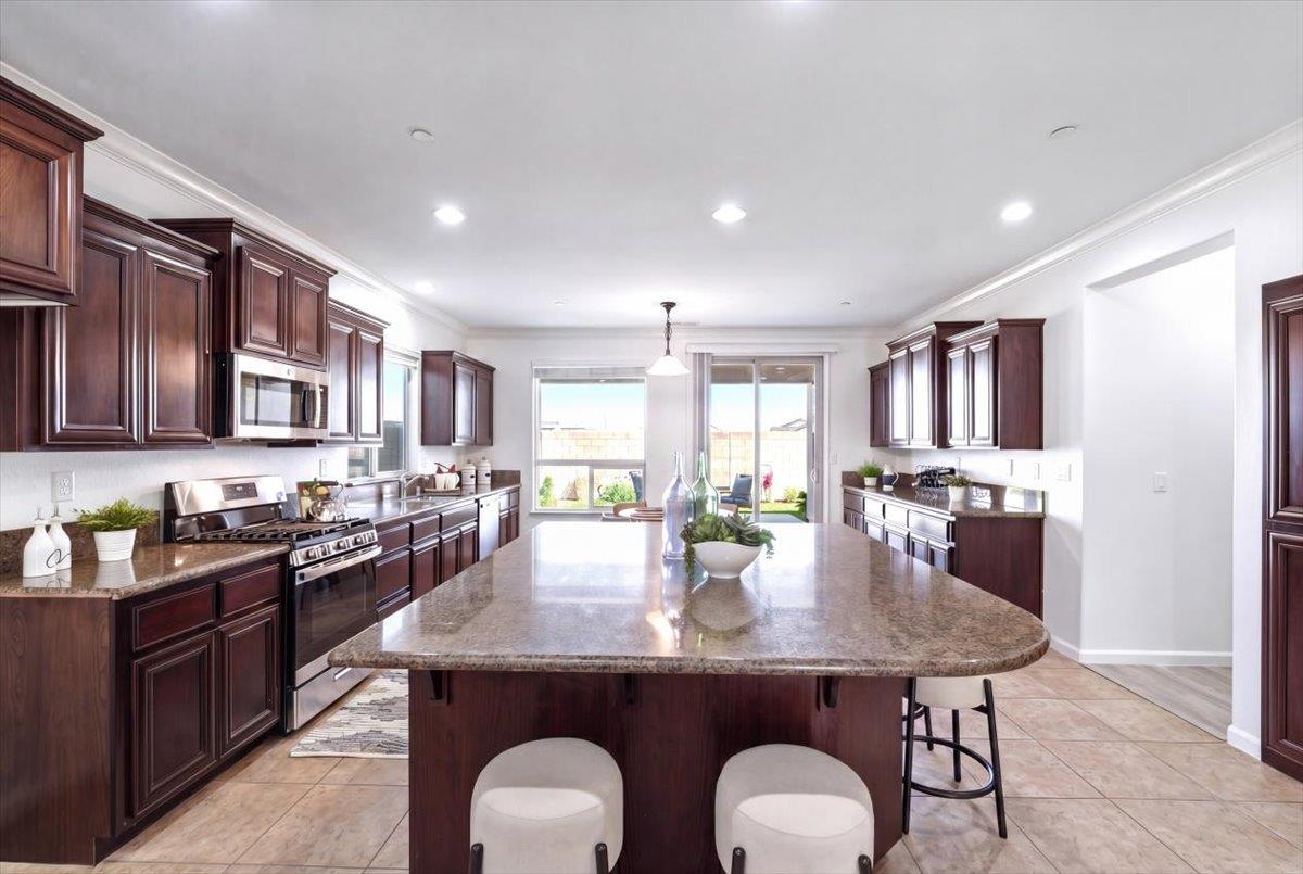 2036 Vignolia Loop Roseville, CA 95747 - Photo 9 of 27 a kitchen with stainless steel appliances granite countertop a stove a sink dishwasher and cabinets with wooden floor